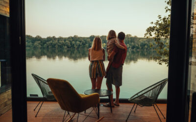 Adorable family of three at the terrace looking at the river A scenic view of family from inside of weekend cottage by the riverside