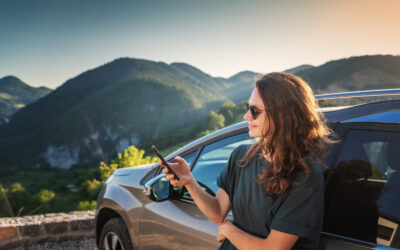 Young beautiful woman traveling by car in the mountains using smartphone at sunset, summer vacation and adventure Young beautiful woman traveling by car in the mountains using smartphone at sunset