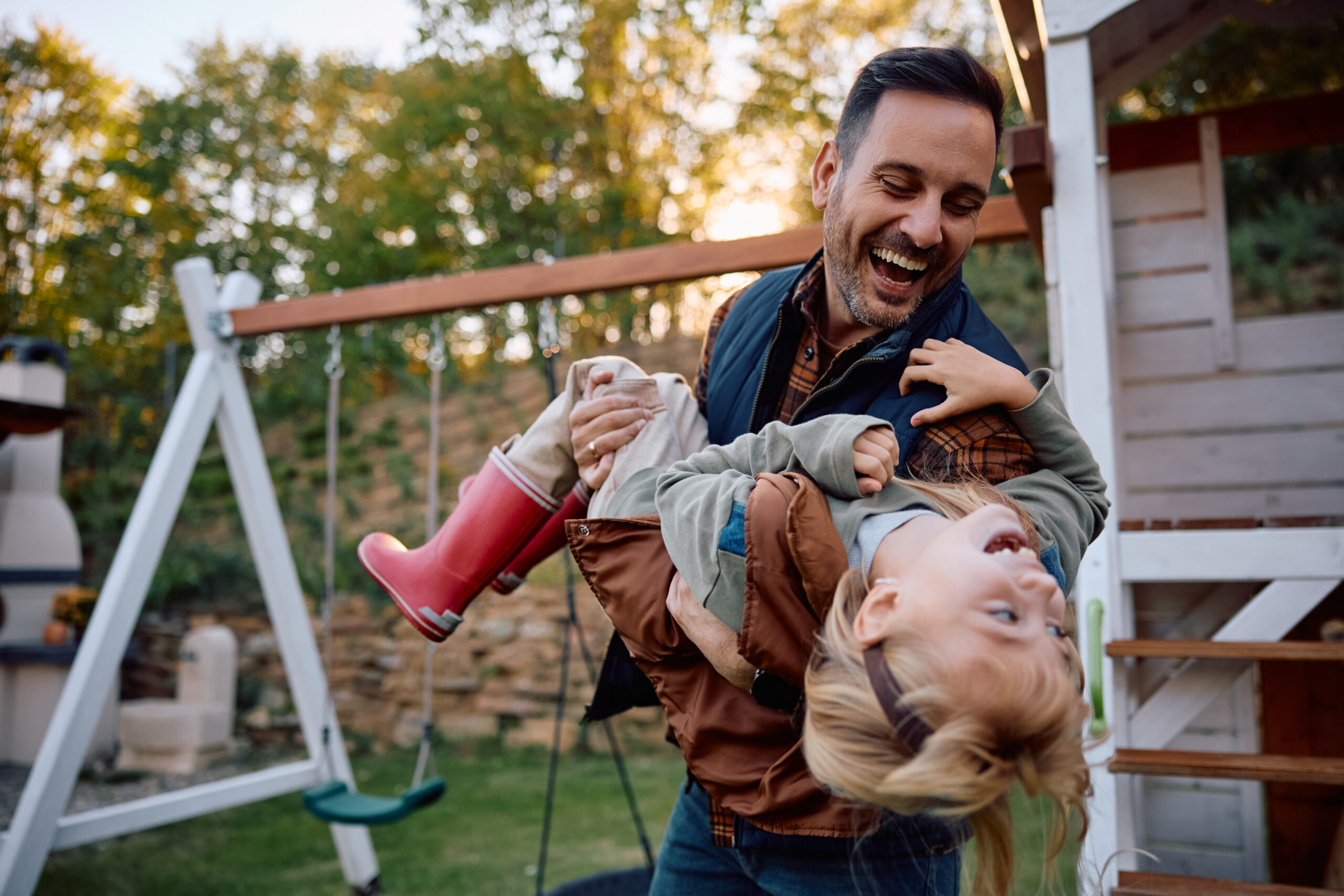 Cheerful father and daughter having fun on the playground during autumn day.