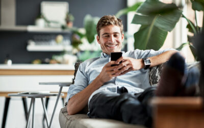 Her messages always make him smile Shot of a happy young man using his cellphone while relaxing on the couch at home